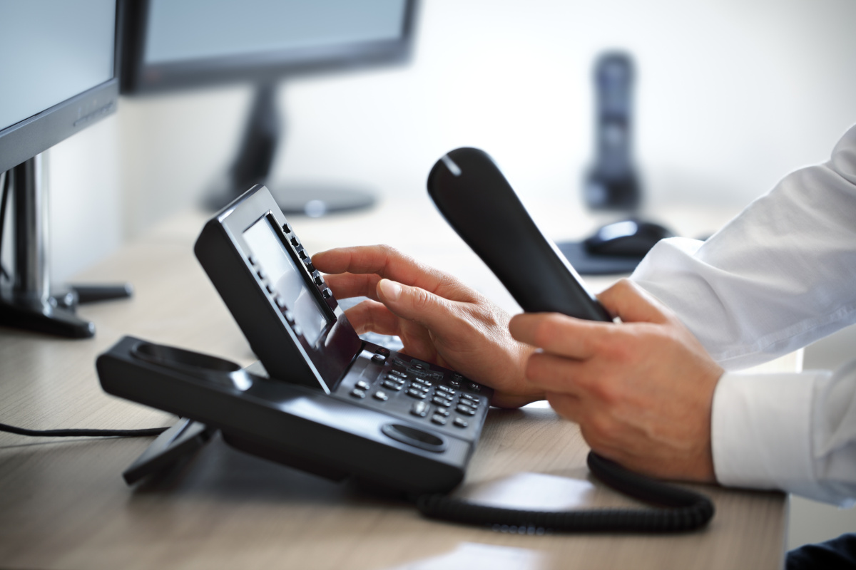 A man dialing on a business phone
