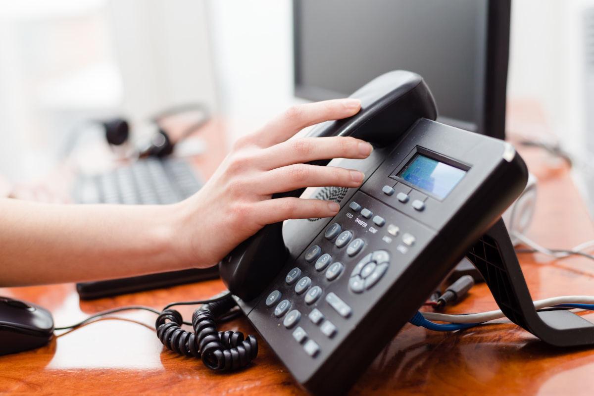 A hadn grabbing a desk phone