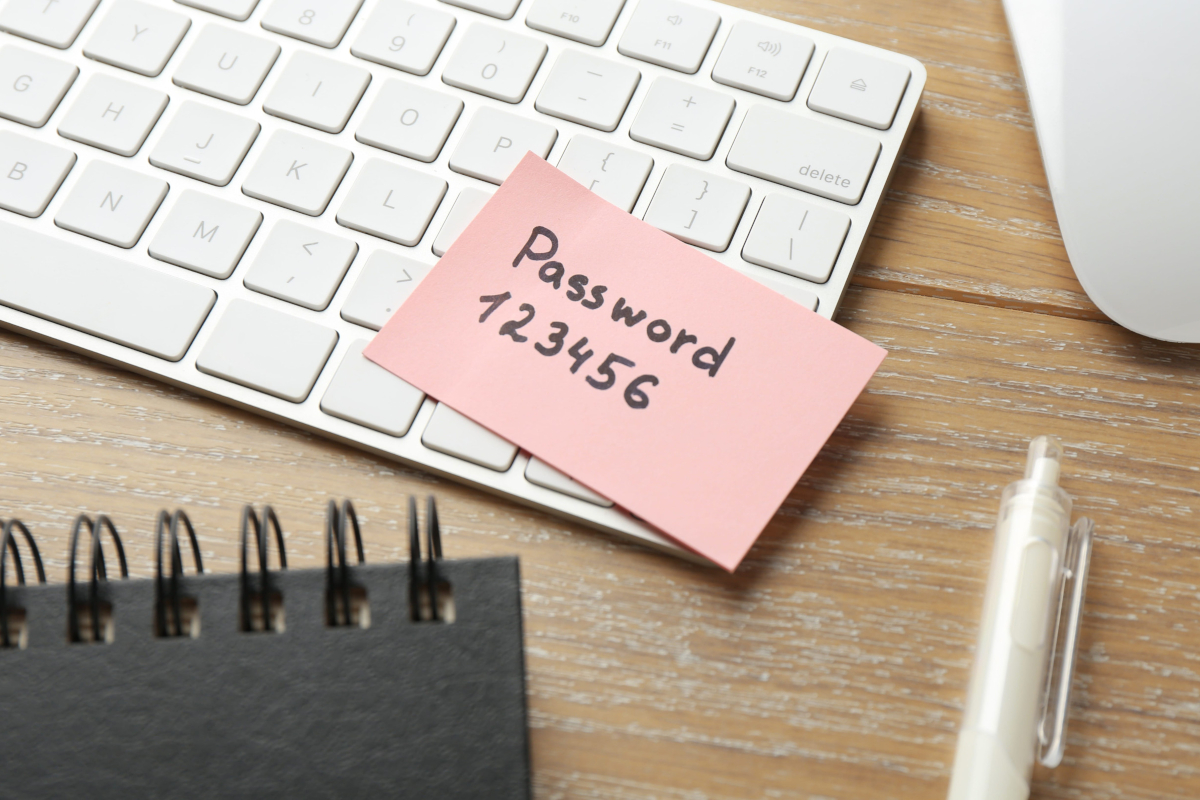 Sticky note with a handwritten password stuck to a keyboard.