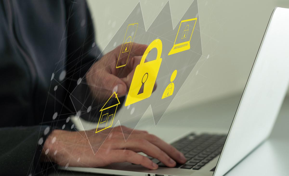 Man using laptop with cybersecurity icons floating around