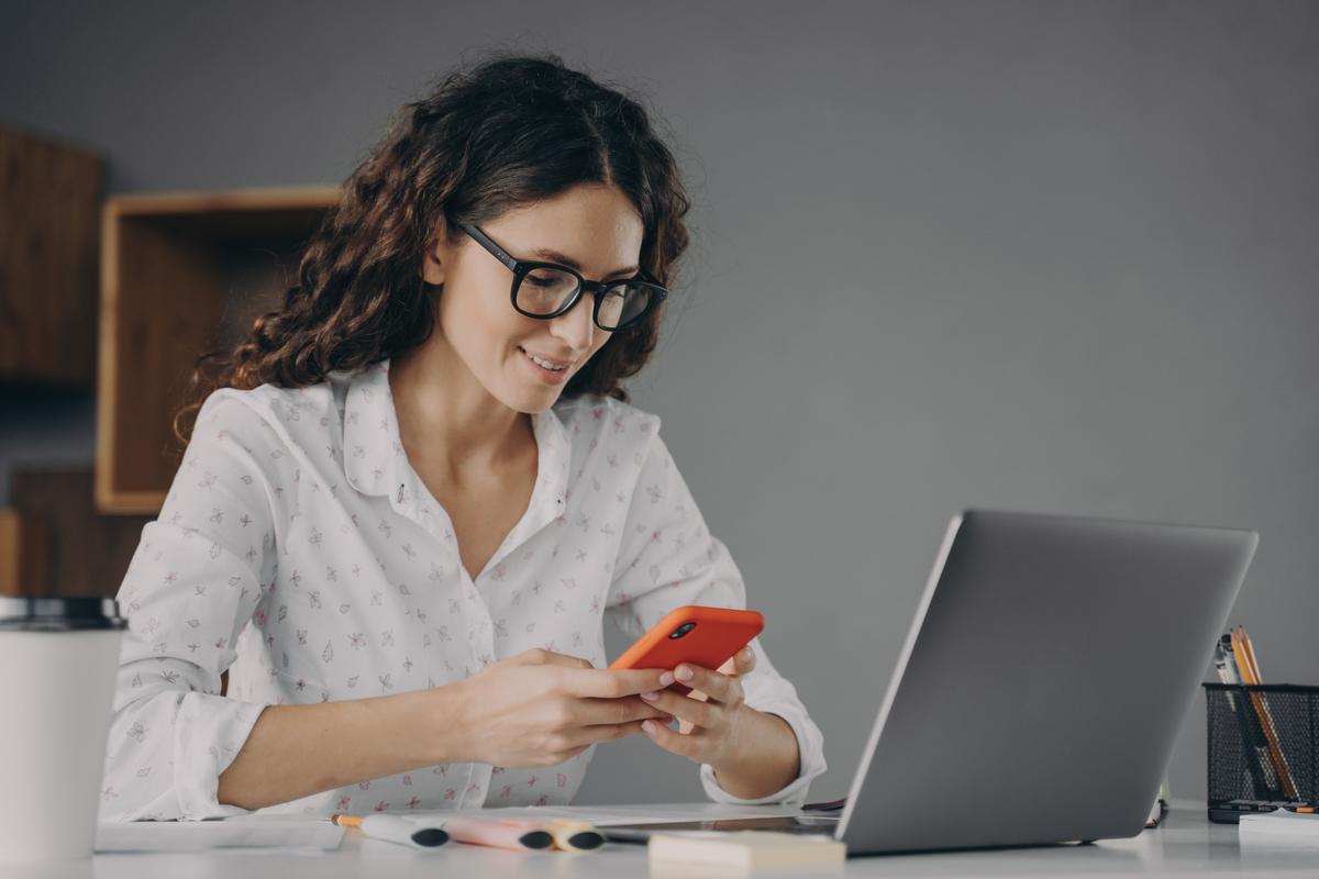 Woman using computer and mobile phone